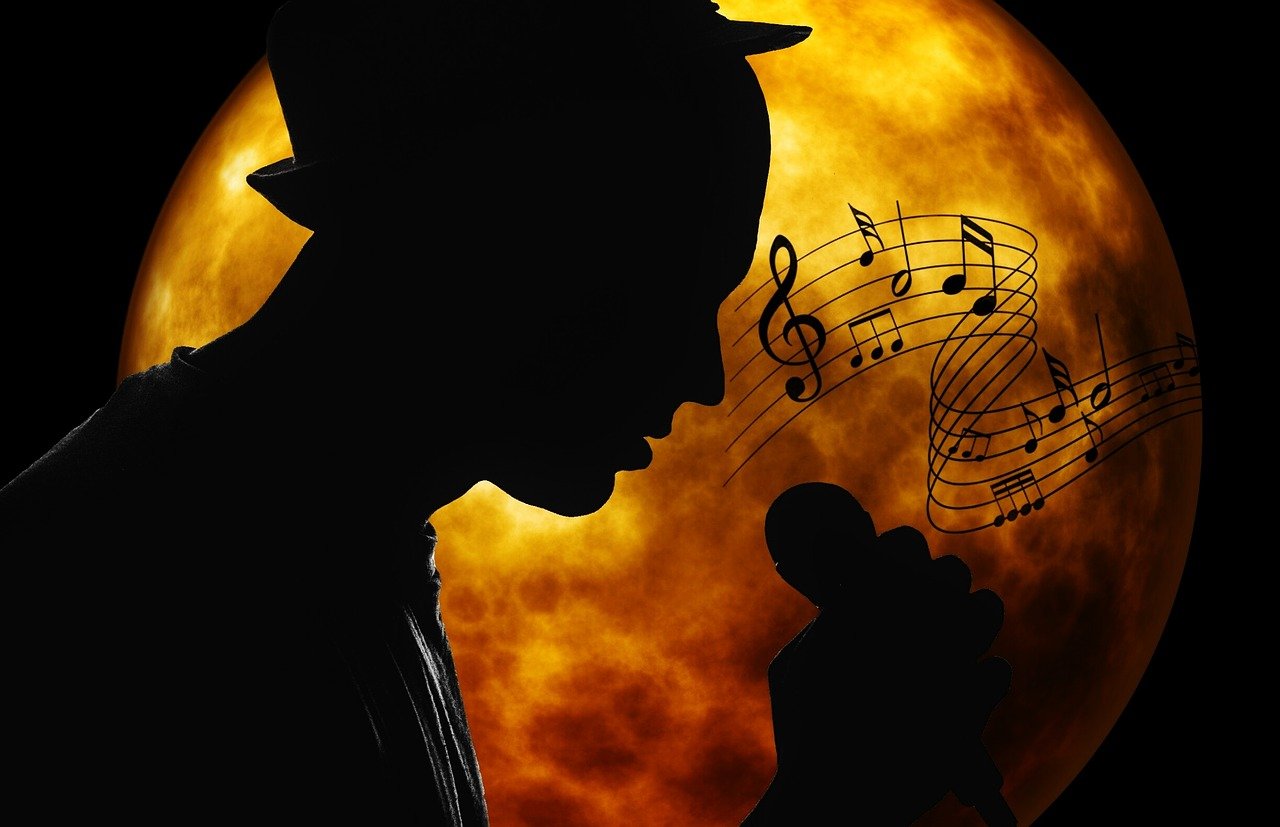 mikrofont kezében tartó énekes fekete sziluettje sárgás-vöröses égitest előtt